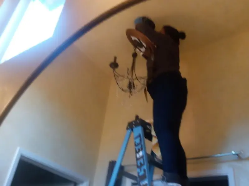 Electrician installing a chandelier in a Ayden residence